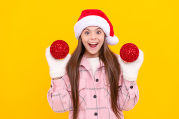 surprised child in santa hat hold christmas decorative ball on yellow background, december.