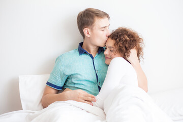 Love couple lying on white bed in morning happy and carring together