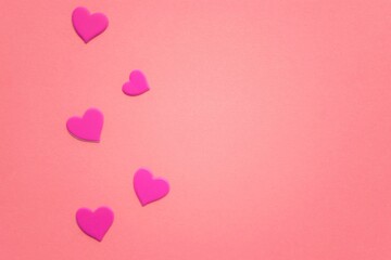 Obraz na płótnie Canvas Lovely magenta hearts on pink paper table. Copy space.