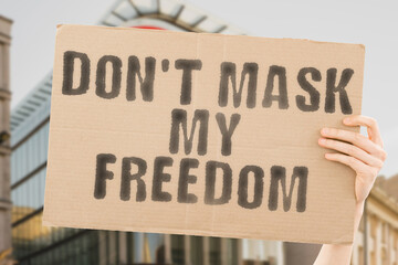 The phrase " Don't mask my freedom " is on a banner in men's hands with blurred background. Protest. Vaccine. Wear. Won. Finish. Medical. Outbreak. Covid19. Against. Remove. No. Forbidden. Free. Off