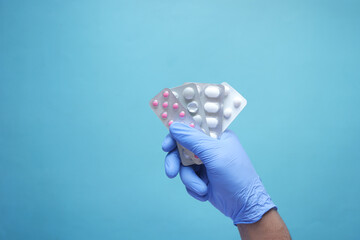top view of hand in latex gloves holding blister pack 