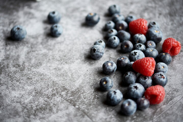 Himbeeren und Blaubeeren vor grauem Hintergrund