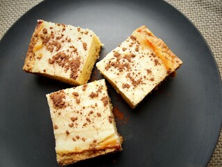 Three cheesecakes on a gray plate. Pieces of cottage cheese pie on a plate, against the background of a tablecloth, close-up. Cheesecake