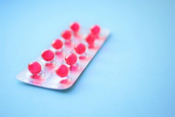 Red pills vitamins translucent capsules on a blue table