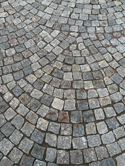 Stone old road, paving stones, closeup. Texture. Fragment of an ancient cobblestone alley. An example of paving from the past. Block paving. In the old days. Historical footprints
