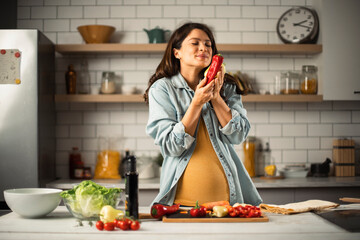 Young woman in kitchen. Beautiful pregnant woman making salad