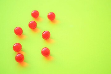 Red round vitamins on a green table. Copy space