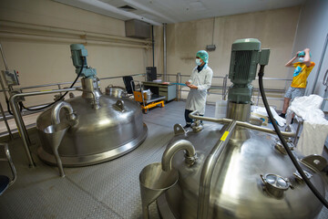 Male workers inspection stainless vertical steel tanks with equipment tank chemical cellar