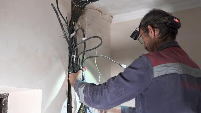 An electrician takes up wiring, assembles a switchboard in a new-build apartment.