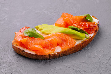 Homemade toast sandwich with salmon, avocado and basil