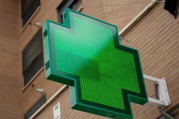 luminous green cross indicating that a pharmacy remains open in the city of Madrid