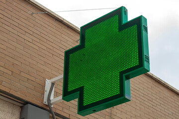 luminous green cross indicating that a pharmacy remains open in the city of Madrid
