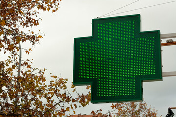 luminous green cross indicating that a pharmacy remains open in the city of Madrid