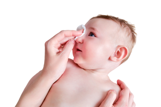 Mother hands wash the face of a happy infant baby with a cotton pad, isolated on a white background. Mom holds hygiene smiling toddler kid on the sofa, six to seven months old