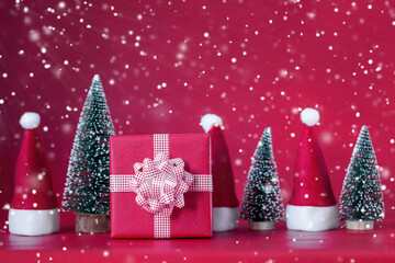 Christmas Composition with red present box and christmas tree and Santa hats on red background. Holiday concept.