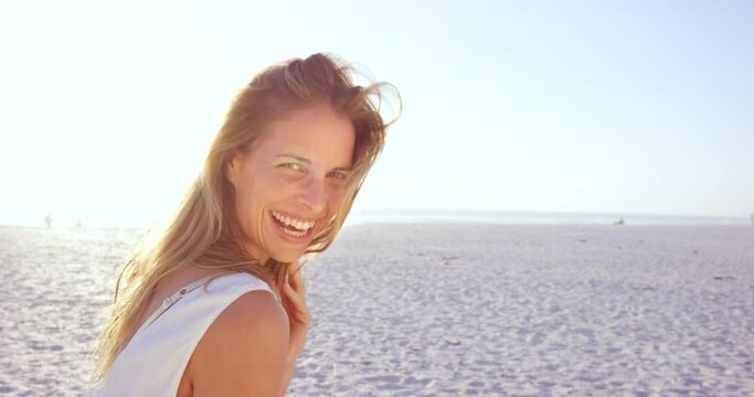 Woman at the beach with smile and face, adventure and happiness with blue sky and beach sand, travel outdoor. Summer vacation by Miami ocean, kiss with lens flare and freedom with nature and sea.
