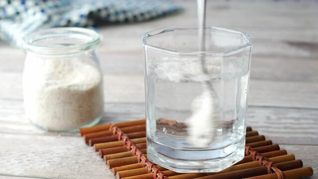 Spoon stirring Psyllium Seeds in a glass of water 