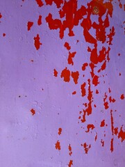 Antigua superficie de metal pintada de púrpura frente a la casa urbana con peladura de color rojo salpicado, forma un diseño abstracto original para los fondos