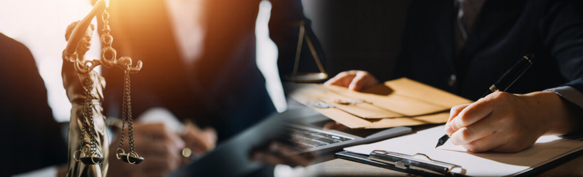 Business and lawyers discussing contract papers with brass scale on desk in office. Law, legal services, advice, justice and law concept picture with film grain effect