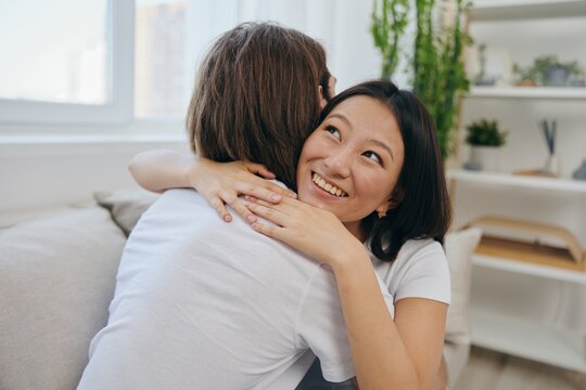 An Asian woman hugs her husband and smiles. The joy of using the family and the good psychological state after the quarrel