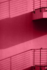 Viva magenta wall with balconies with shadows. Minimal abstract concept. Color trend year 2023.