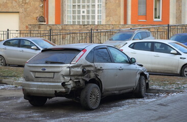 A broken gray car is parked on the street, Kollontai Street, St. Petersburg, Russia, December 2022
