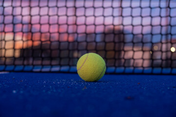 selective focus, a ball on a paddle tennis court at sunset. racket sports courts