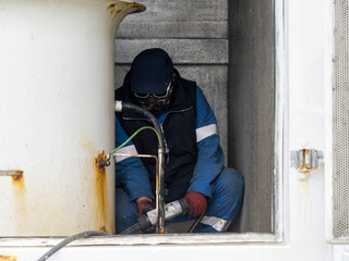 a ship crew is working or chipping during maintenance period on a cargo ship