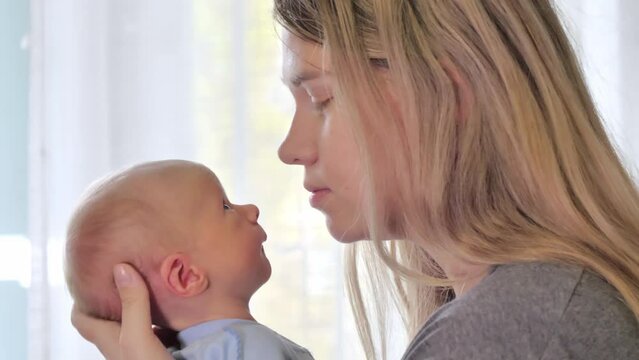 Mom kissing her newborn baby. Love and tenderness. Family concept. Slow motion shot