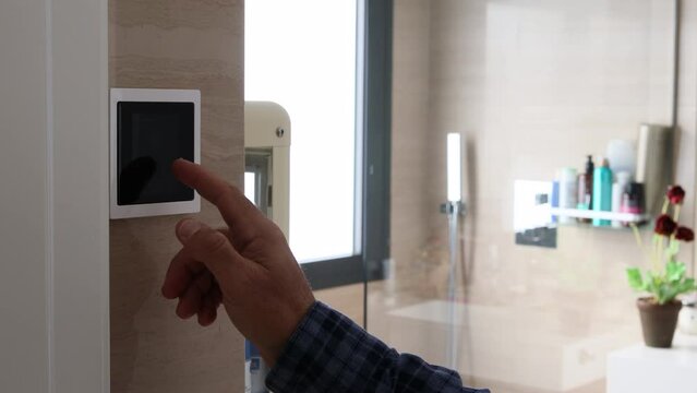 Close-up of man's hand lowering the blinds on a home automation screen in the bathroom. Home automation. Energy saving concept
