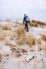 Man trekking on dunes by the sea at autumn