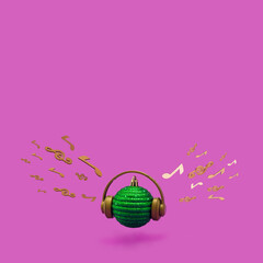 Green Christmas bauble with headphones, musical notes and violin key on a vibrant purple background. Concept of Christmas, New Year and winter holidays party, music and happiness. Good Vibes.