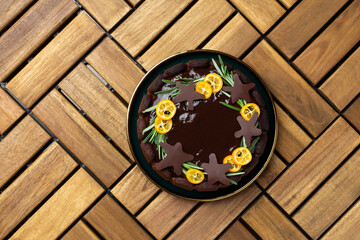 Christmas chocolate cake with oranges and rosemary on a wooden table