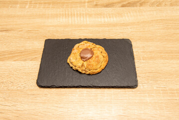 Delicious fluffy cookie with chocolate inside on a black slate plate