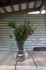Vase with a bouquet of flowering cut heather on the table in the village house