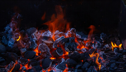 Fototapeta na wymiar Charcoal and embers burning at full capacity at its peak in a metal barbecue