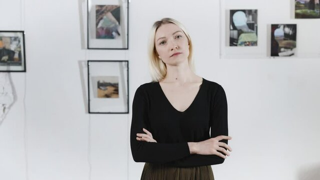 Portrait of a beautiful blonde, in an art gallery. A woman poses against the backdrop of abstract paintings by a contemporary artist.