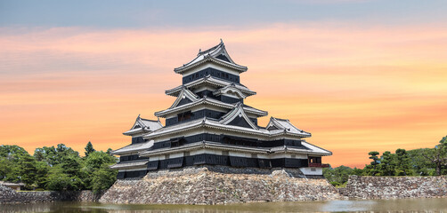 Matsumoto Castle in Matsumoto City Nagano Prefecture In autumn, the change of time from day to night The golden light of the sun shines to the castle with a reflection of the water