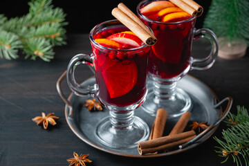 Two glasses with hot mulled wine with orange and spices on a wooden background. Hot drinks of winter and autumn. Autumn or winter still life.
