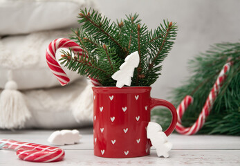 A cup cheerful atmosphere, branches of a green Christmas tree. New Year 2023 is approaching