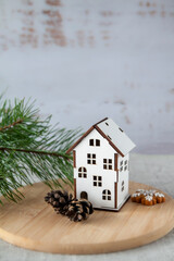 White toy house made of pine cones and green fir branches with needles. New Year's and Christmas festive mood