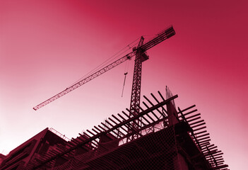 Silhouette of construction tower crane with sunset background at evening time. New 2023 trending...