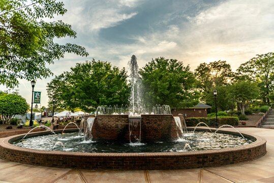 A fountain in Greer with water cascades, surrounded by green trees, with a house in the background