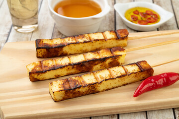 Grilled Rennet or Coalho cheese on a wooden board with sugar syrup and pepper
