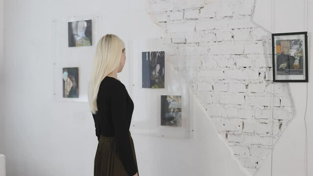 Beautiful blonde in the art gallery. A woman looks at the work of a contemporary artist.