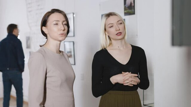 Attractive women in an art gallery at an exhibition of a contemporary artist. Visitors discuss art.