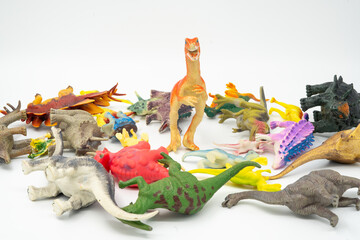 A large group of children's toy dinosaurs that are knocked down and lying down and one standing...
