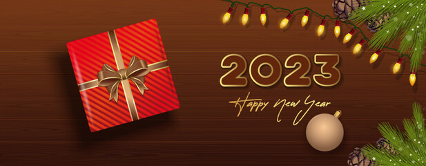 Fototapeta na wymiar 2023 Happy New Year. Wide horizontal vector Christmas banner. Gift box, Christmas tree garland, Christmas tree toy and Christmas tree branches on a wooden table, top view