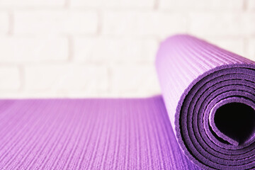 Purple exercise mat close to the brick wall in the fitness room. Sports and leisure activity backgrounds