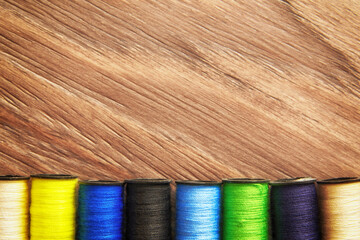 Pink and turquoise colored thread reels row on the tailor table. Embroidery theme backgrounds. Copy...